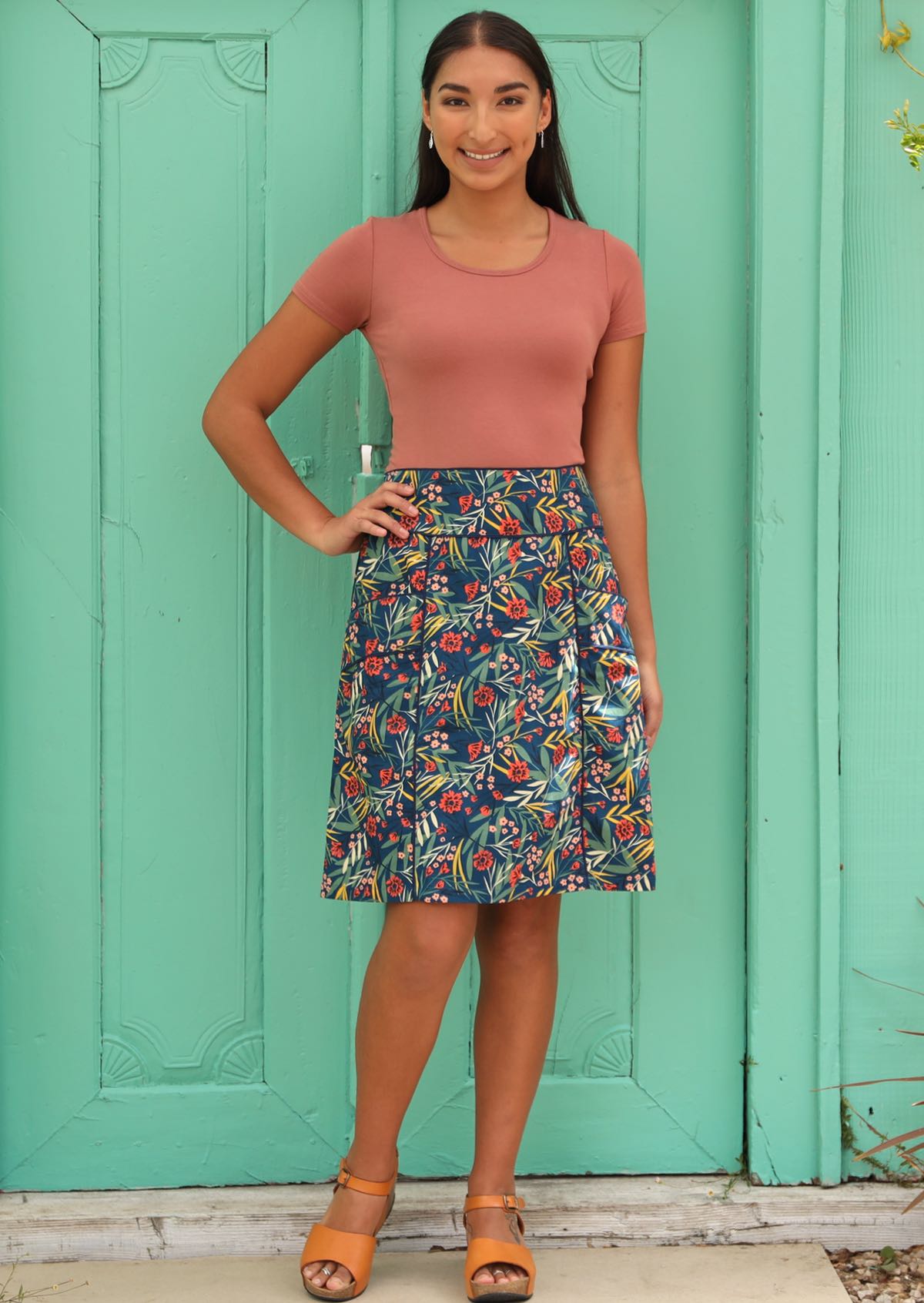 Model wears blue based floral skirt with piped detail. 