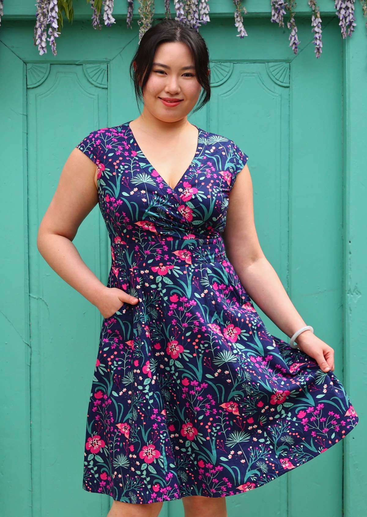 Woman in Alice Dress Dianthus retro style 100% cotton navy blue floral with cross over bodice and pockets fit and flare style dress