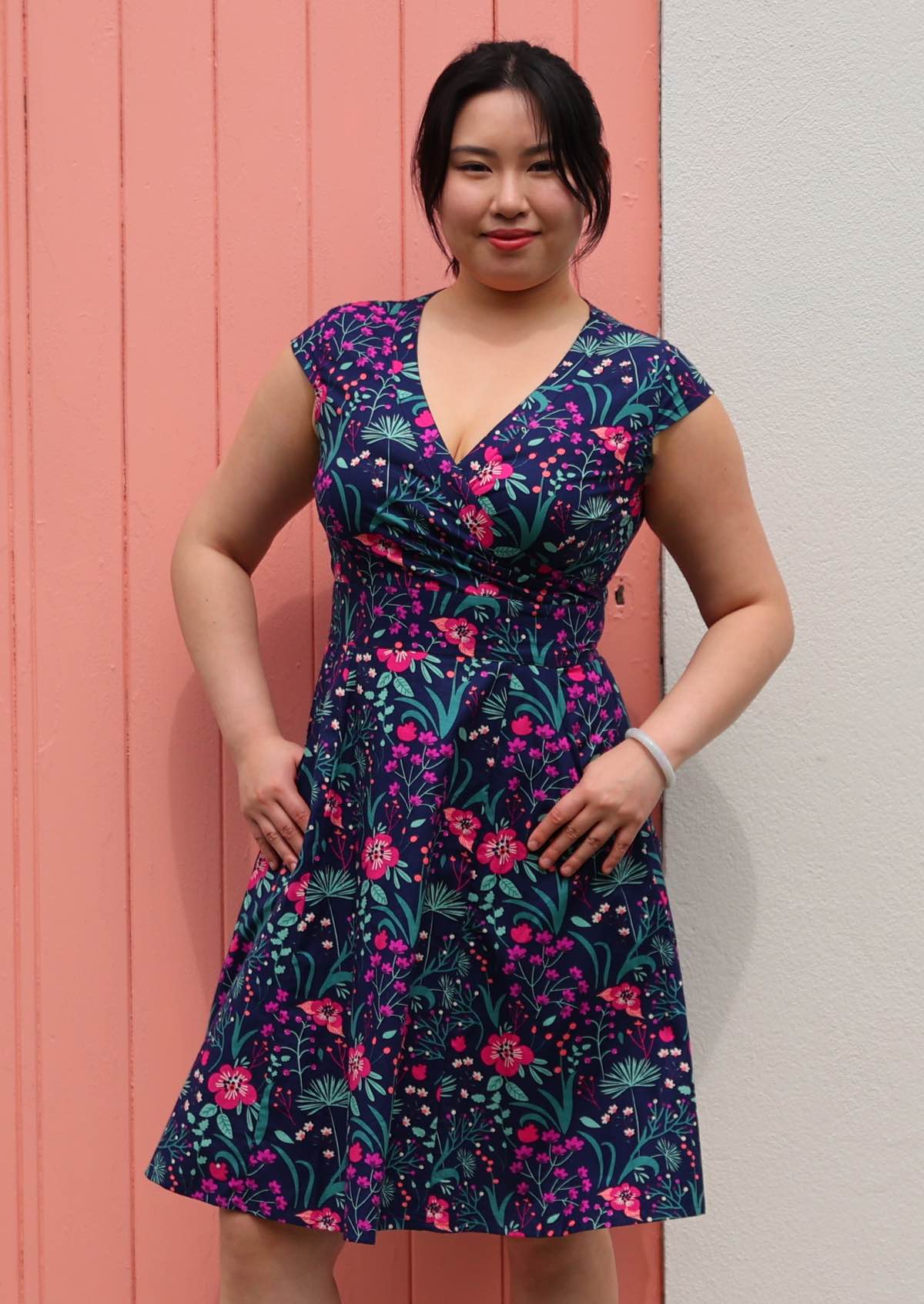 Woman in Alice Dress Dianthus retro style 100% cotton navy blue floral with cross over bodice and pockets fit and flare style dress thumbs in pockets