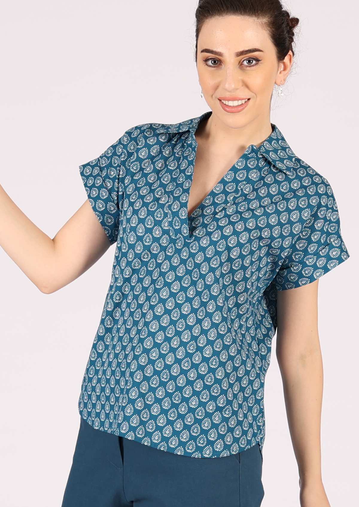 Model wears blue top with a collar and short sleeves with a folded cuff. 