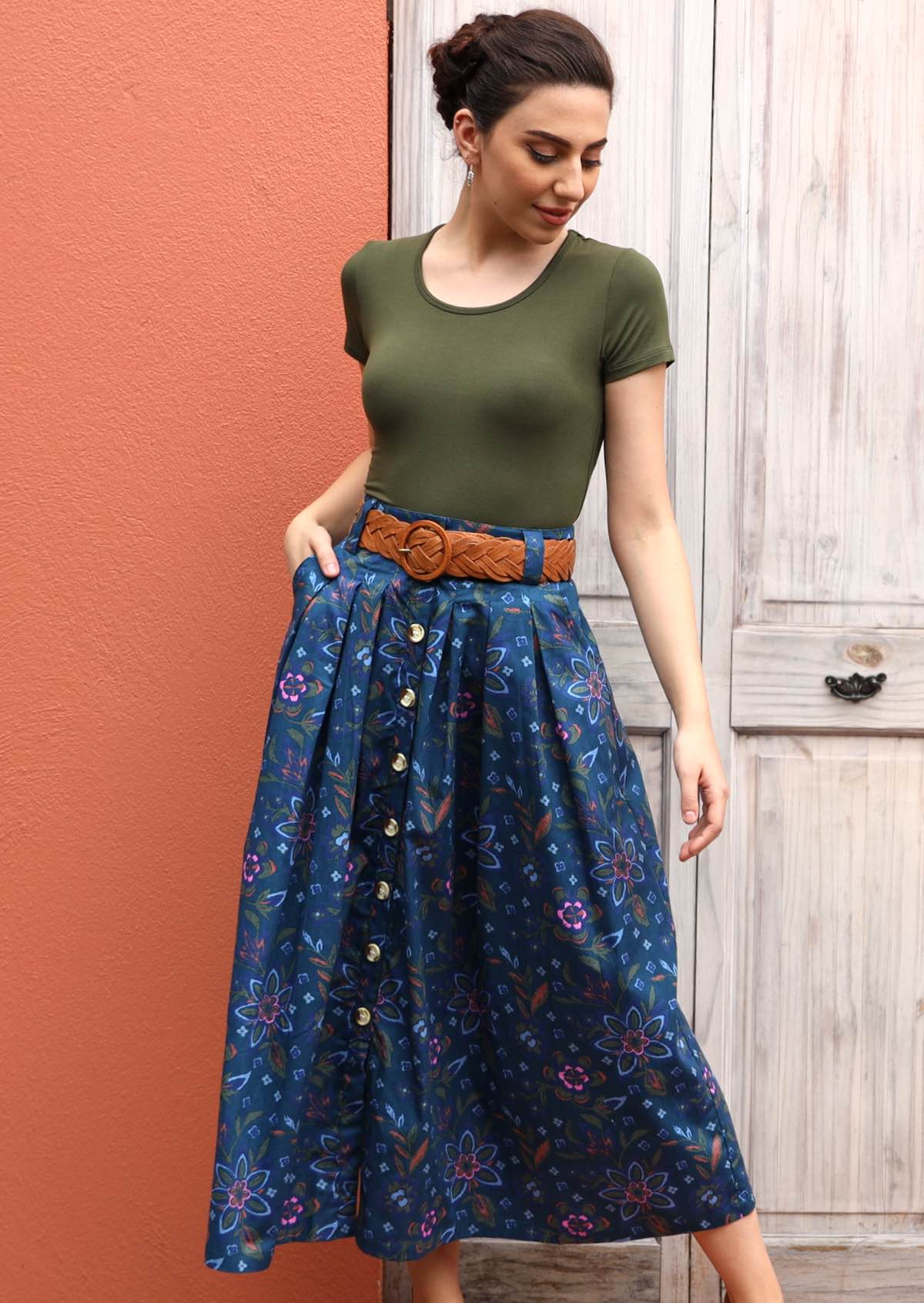 Model pairs blue cotton skirt with a brown belt and short sleeve top. 