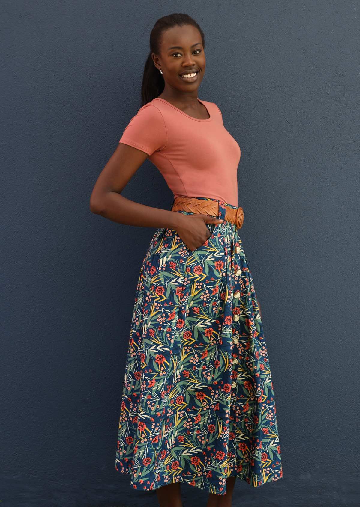 Model wears blue floral cotton skirt with belt loops and pockets