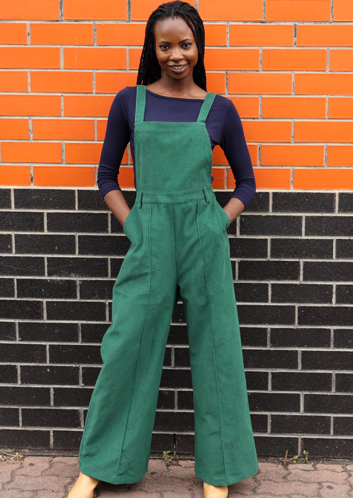woman wearing green cotton corduroy overalls with hands in pockets