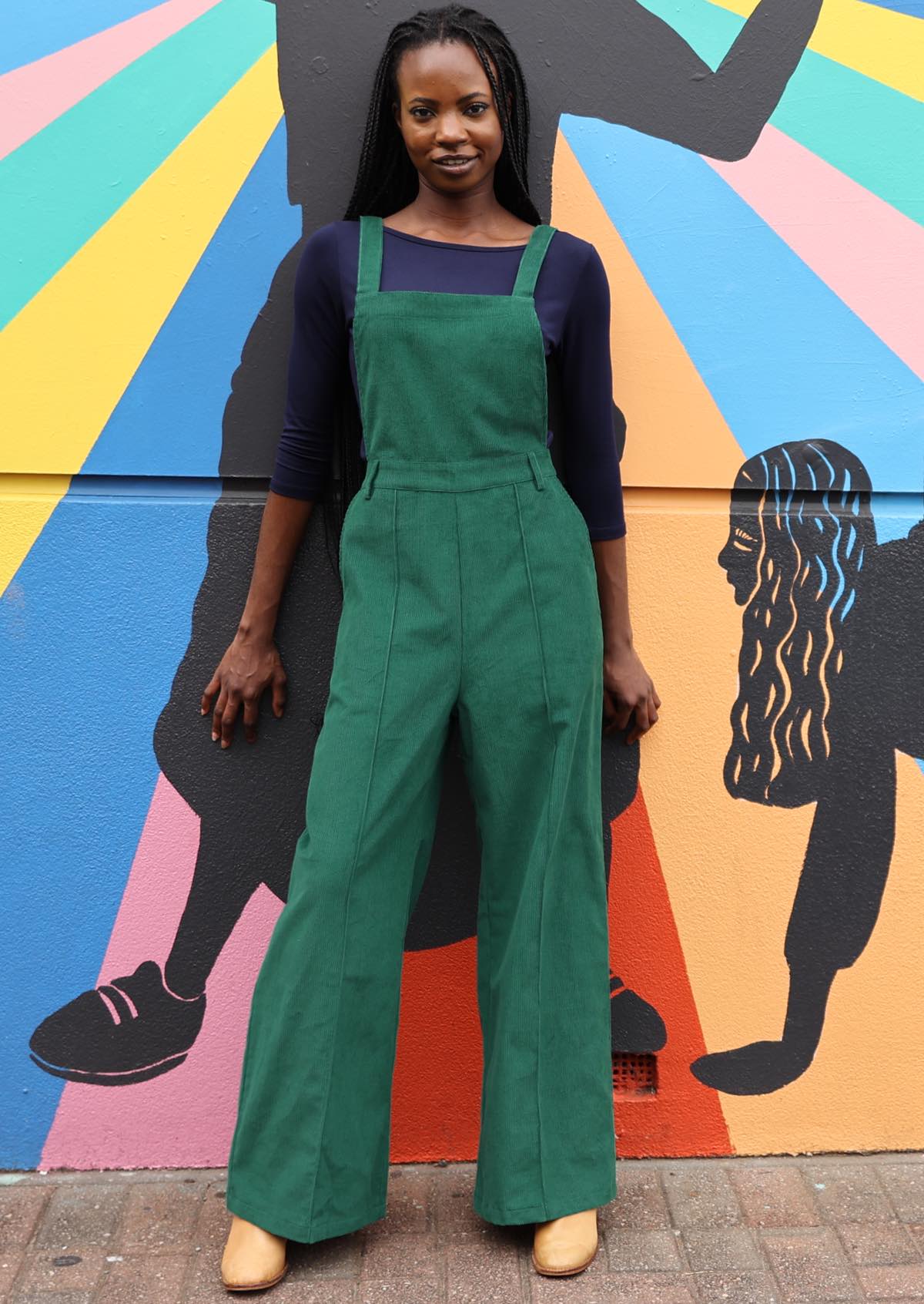 woman wearing green cotton corduroy overalls over long sleeve navy rayon top