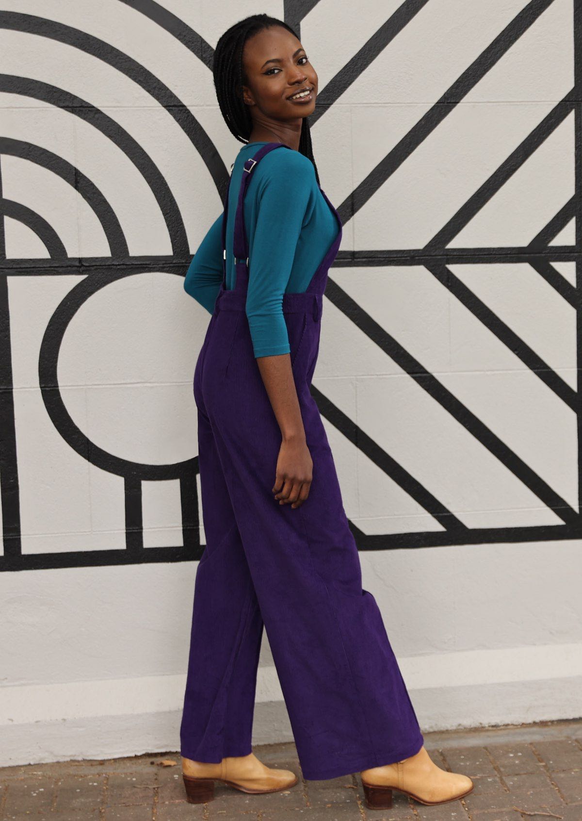 side view of woman wearing purple corduroy overalls 