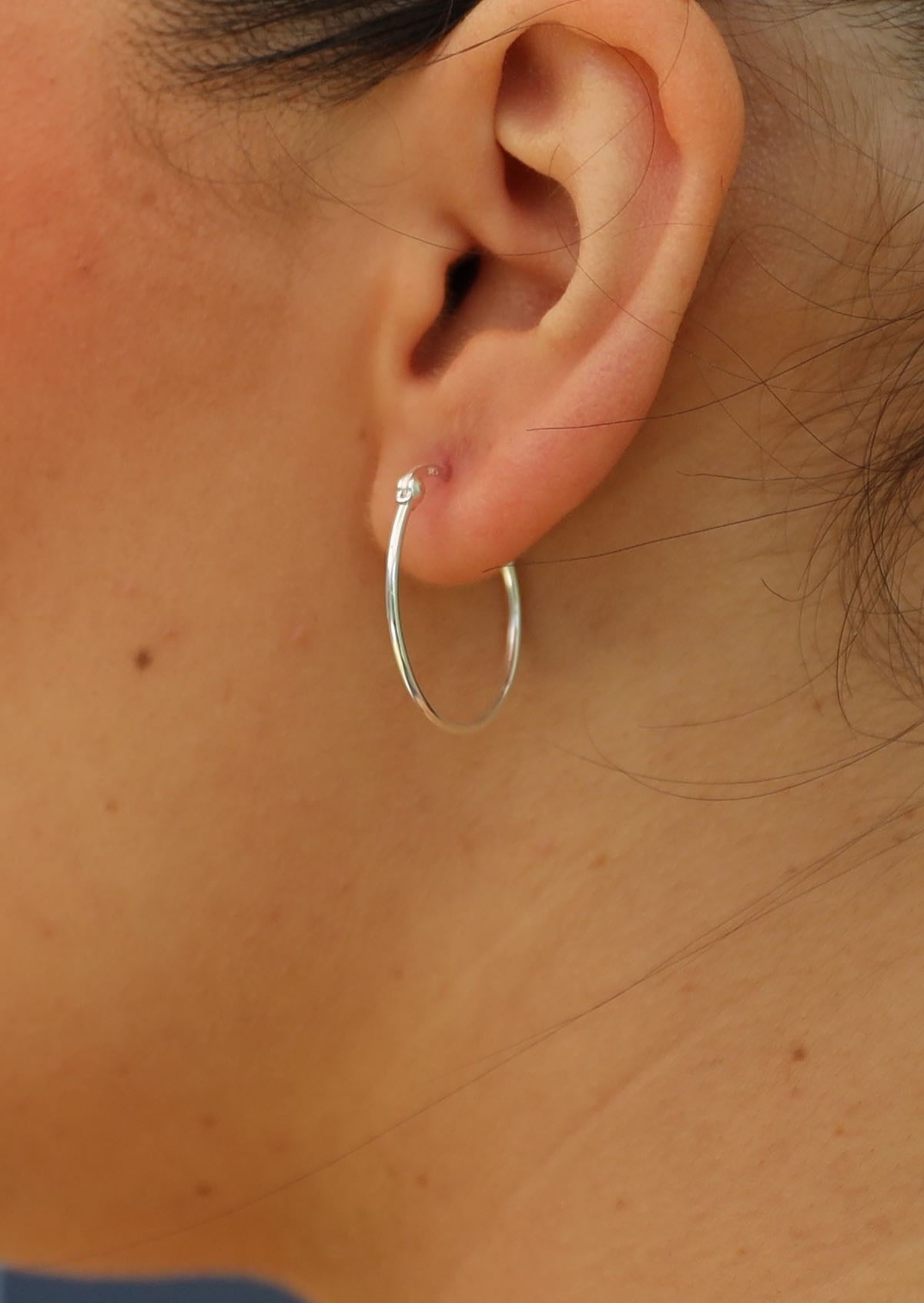 Slim sliver hoop earring on ear