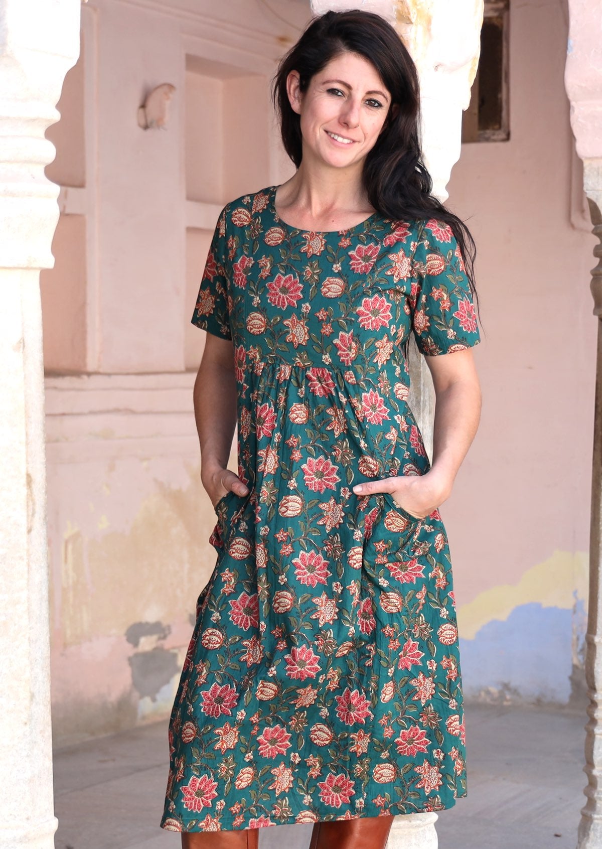 Model wears floral printed dress with green base, T shirt style short sleeves and pockets.
