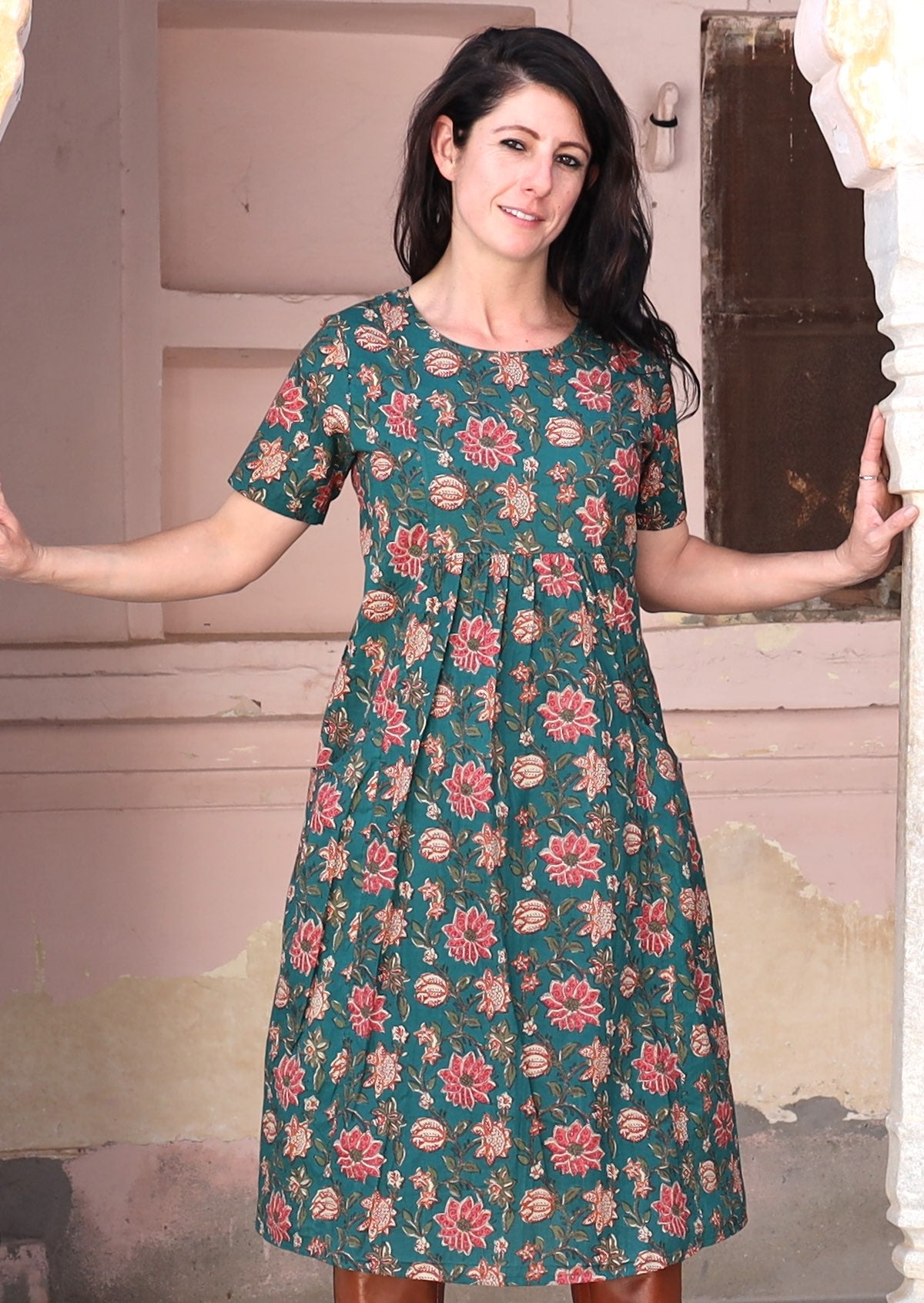 Model stands in cotton dress with empire waistline and small gathers under the bust.