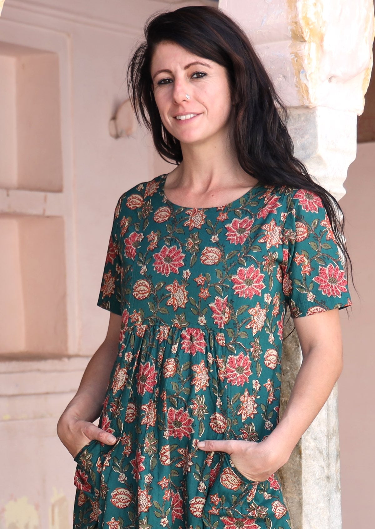 Close up of model in relaxed fit cotton dress with round neckline and hands in pockets.