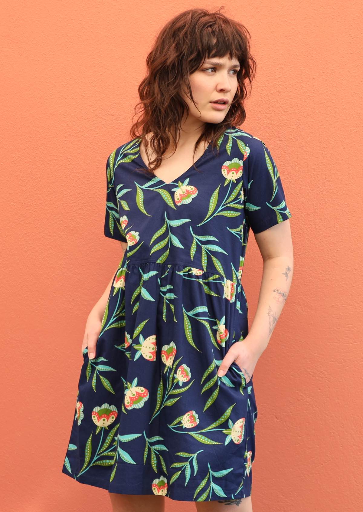 Model wears 100% cotton dress with blue base and a floral design 