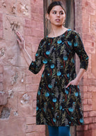 Model wears botanical print with teal on black base cotton dress