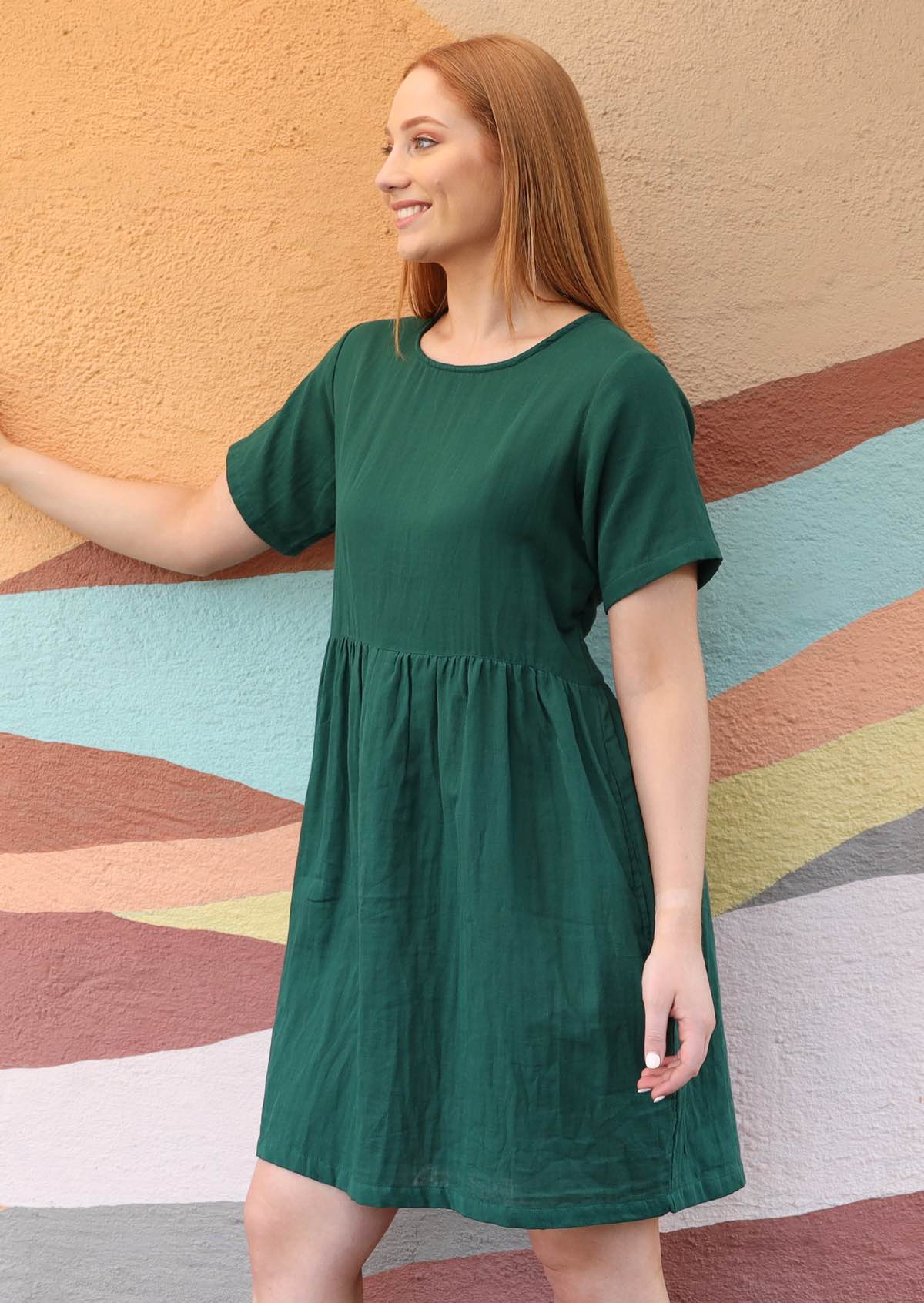 model wearing green mabel dress standing side on