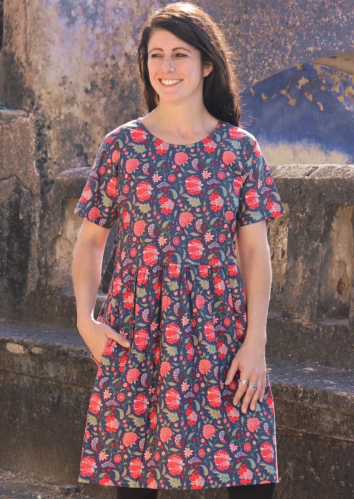 Woman wearing 100 percent cotton blue base retro dress with leaf and floral print with one hand in pocket