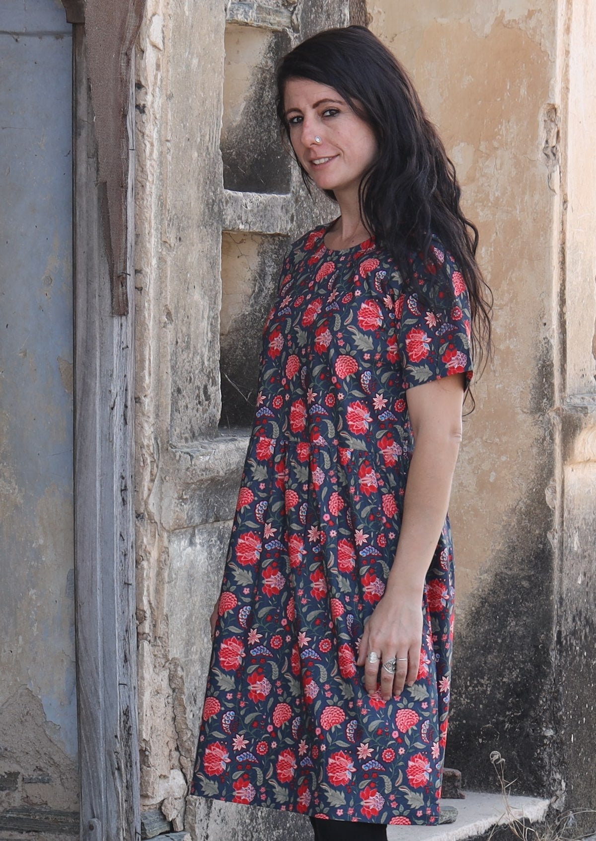 Woman standing sideways wearing 100 percent cotton blue base retro dress with leaf and floral print