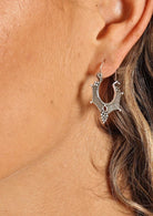 woman's ear wearing large tribal style silver hoop earrings