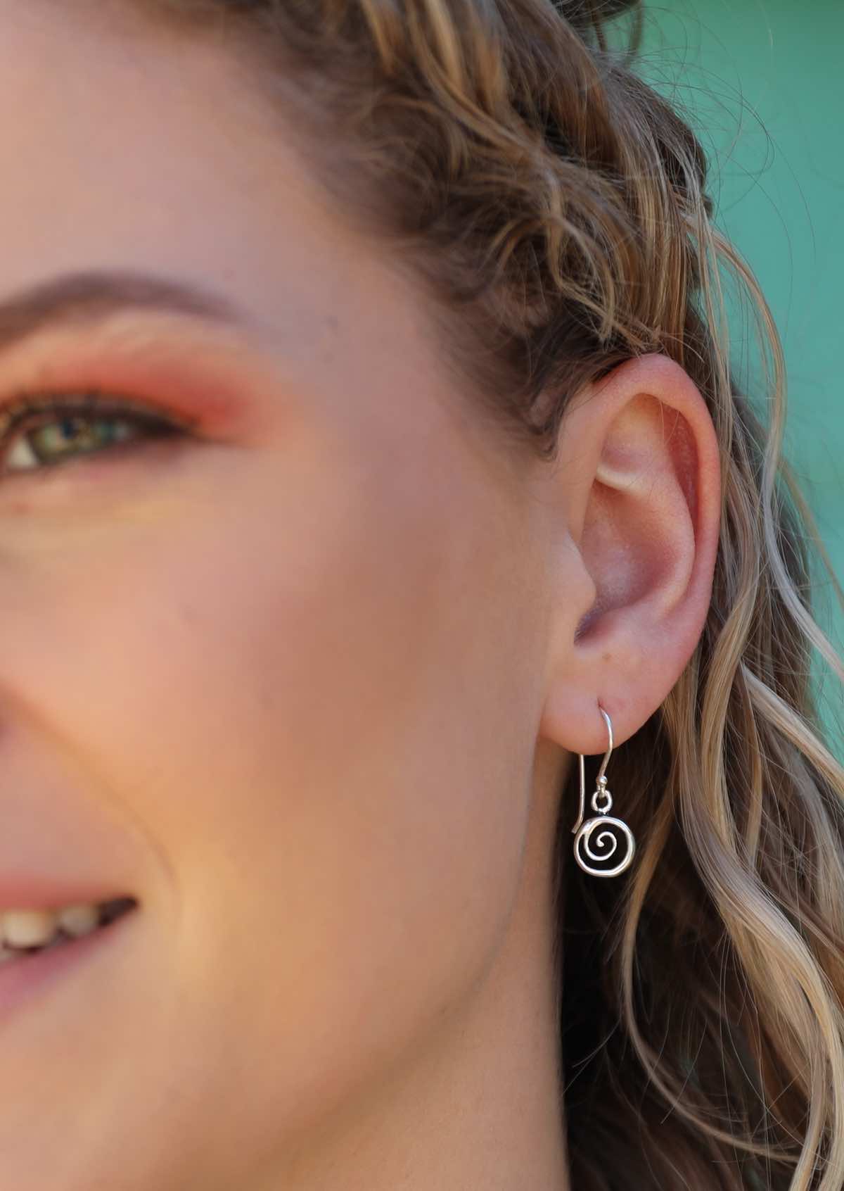 woman wearing small silver spiral dangly earrings