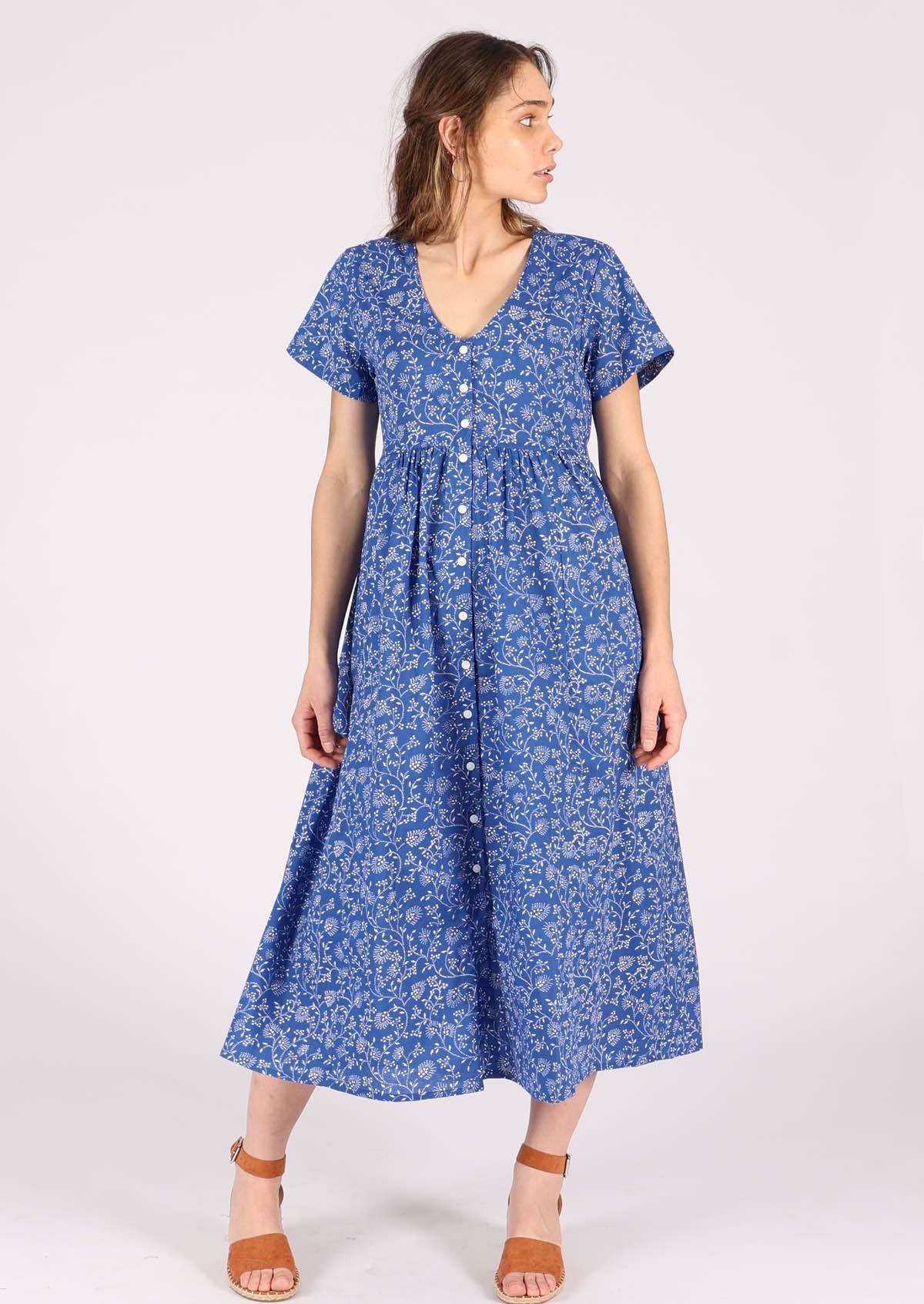 Model wears blue base white floral print cotton midi length button through relaxed fit dress