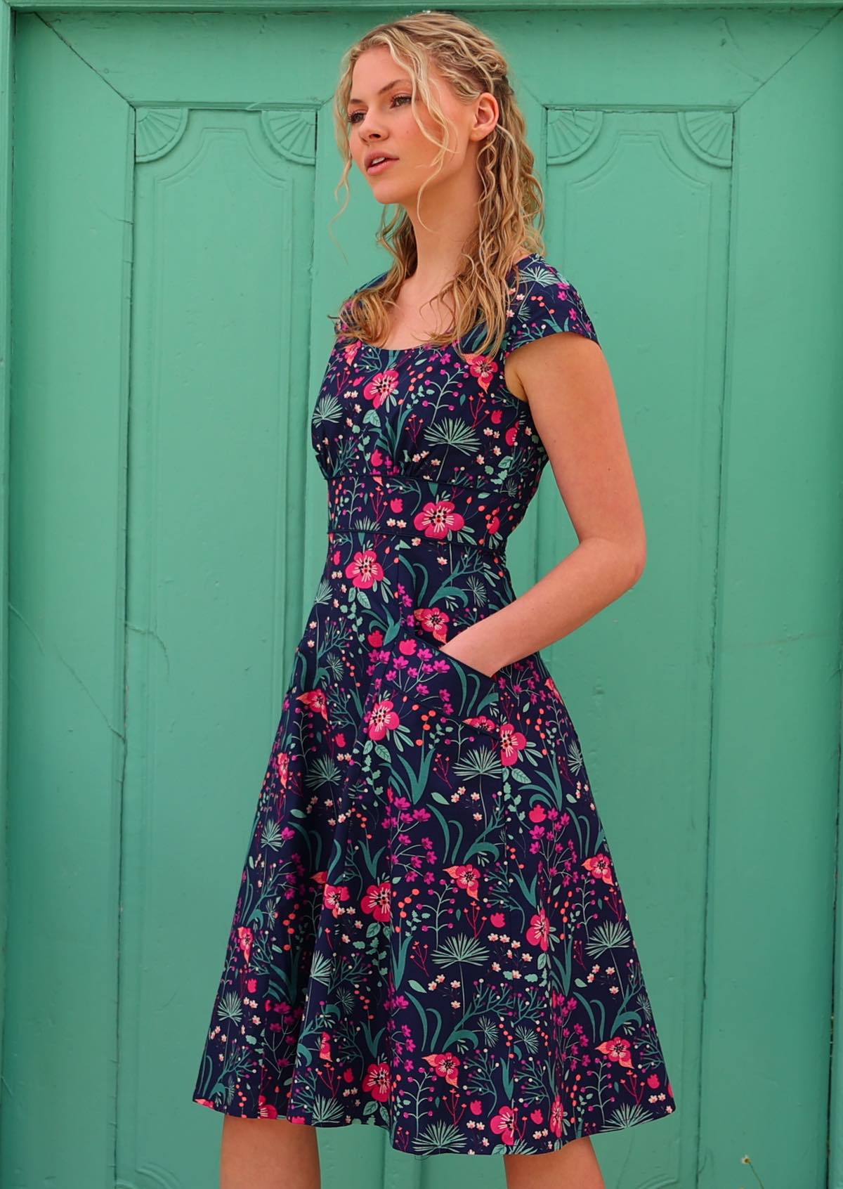 woman in retro inspired Scarlett Dress Dianthus in a navy, purple, pink and aqua floral print on 100% cotton