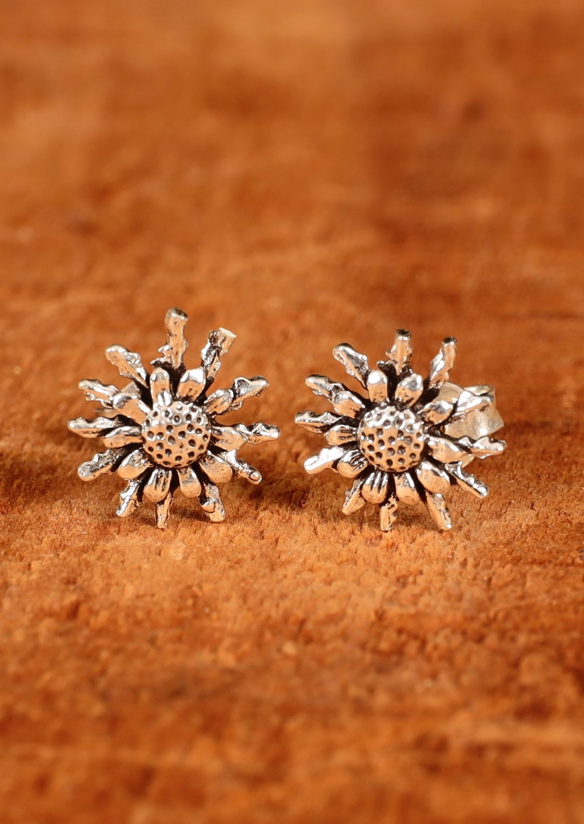 92.5% silver floral studs sit on wood for display.