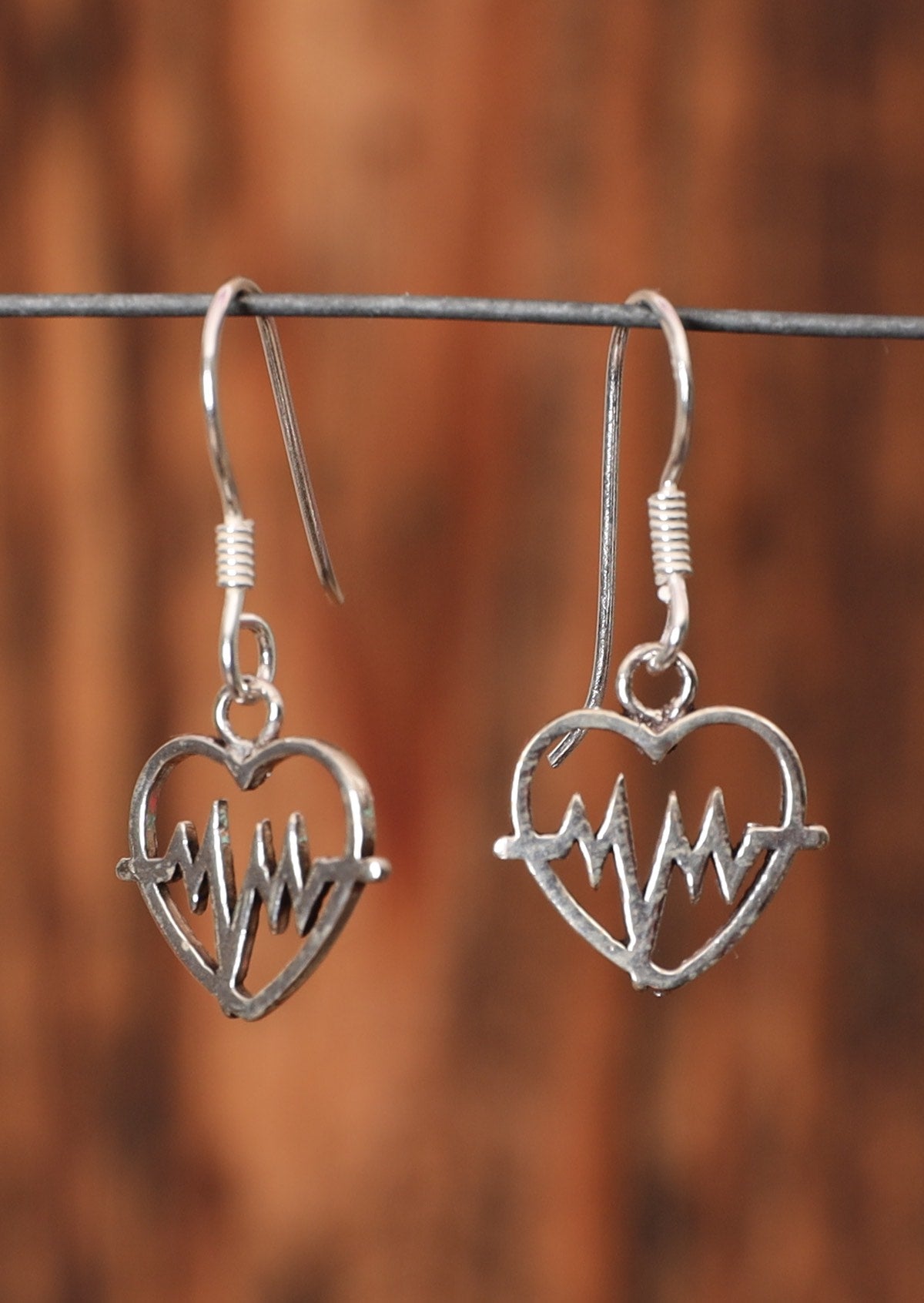 92.5% silver heartbeat earrings with hook sit on wire for display.