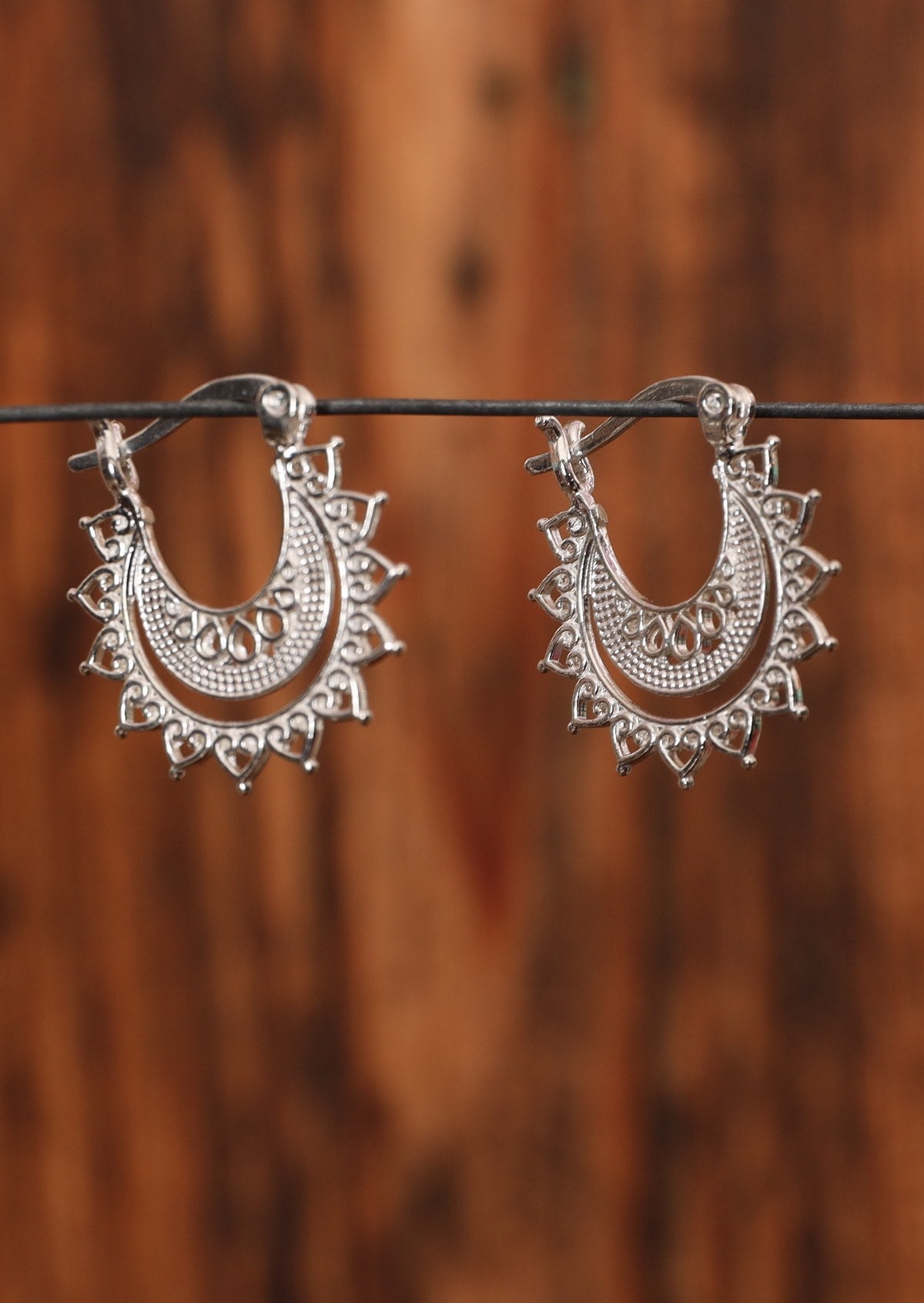 92.5% silver layered lace earrings with a latch clasp sitting on wire for display.