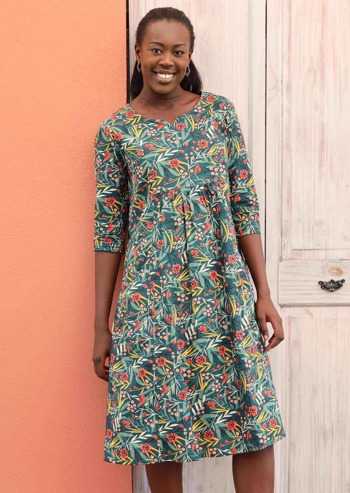 Model wears a below the knee length dress with a floral pattern. 
