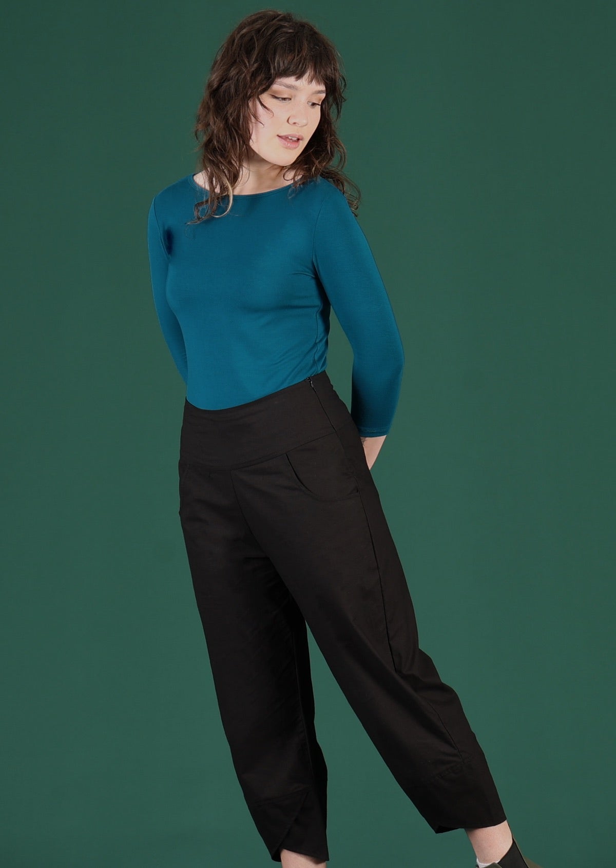Model wears black pants with a side zip and pockets. 