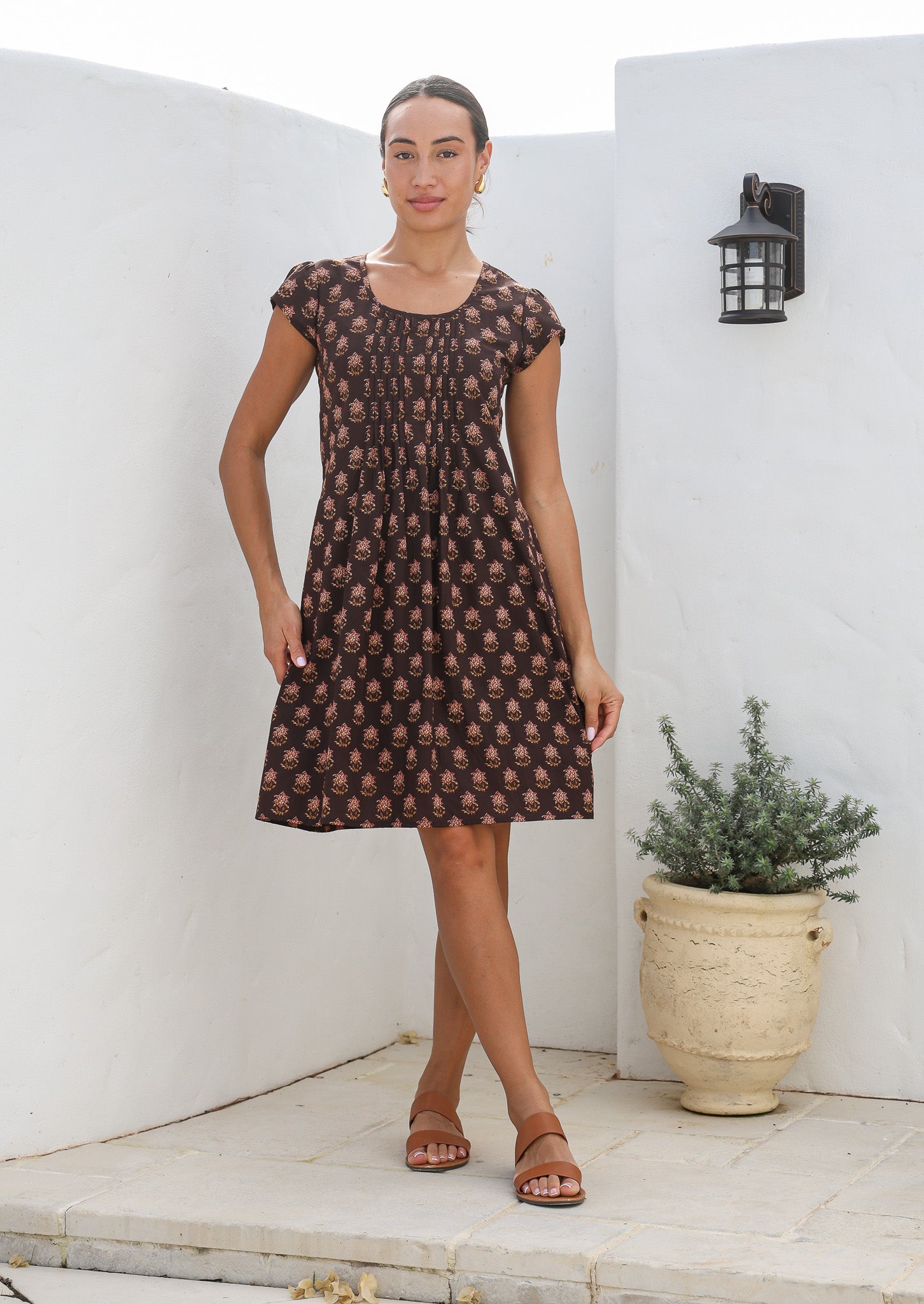 Women wears 100% cotton dress with pleated bodice, round neckline and short caped sleeves.
