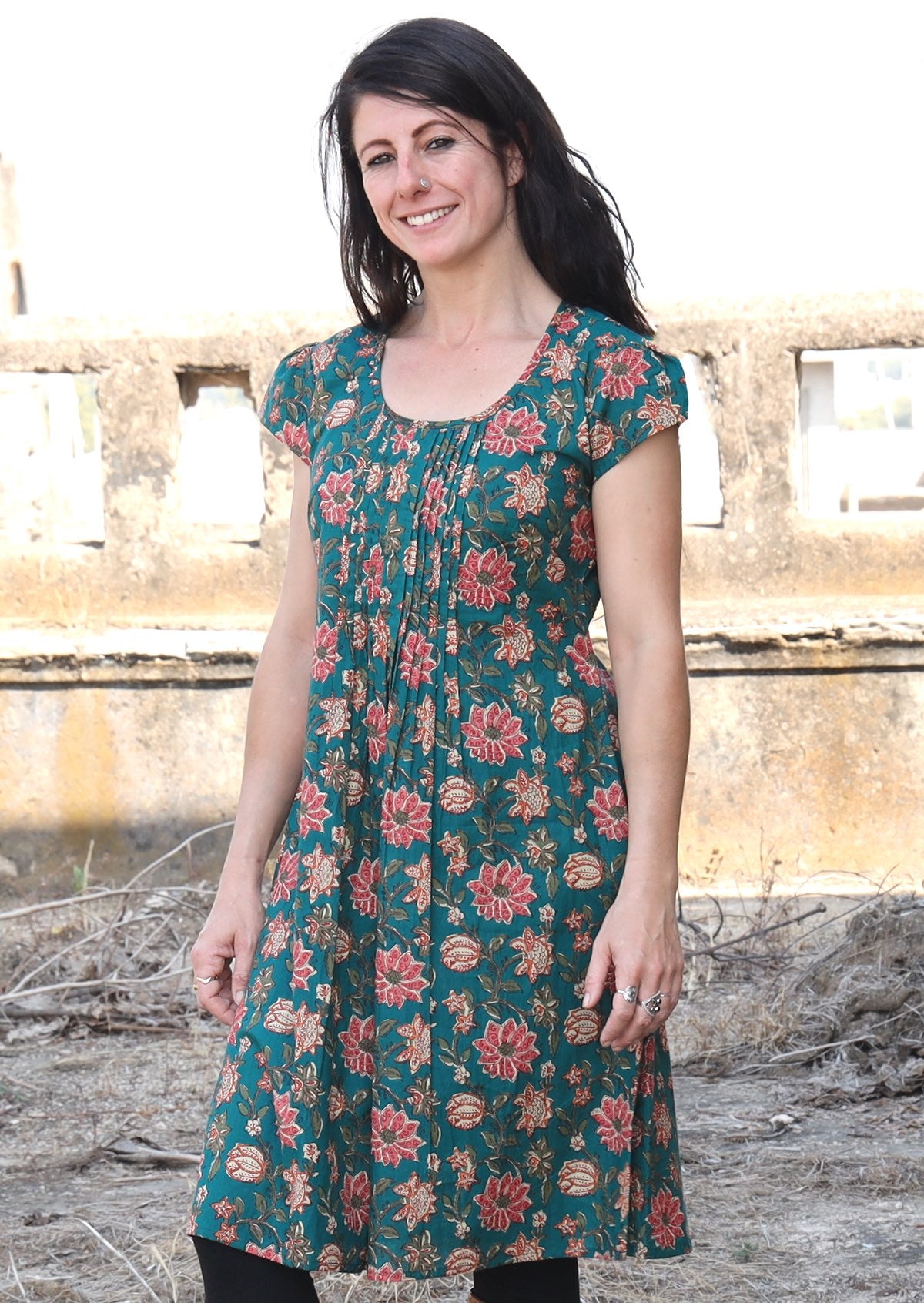 100% cotton knee length dress with short caped sleeves, round neckline and pleats across the bodice.
