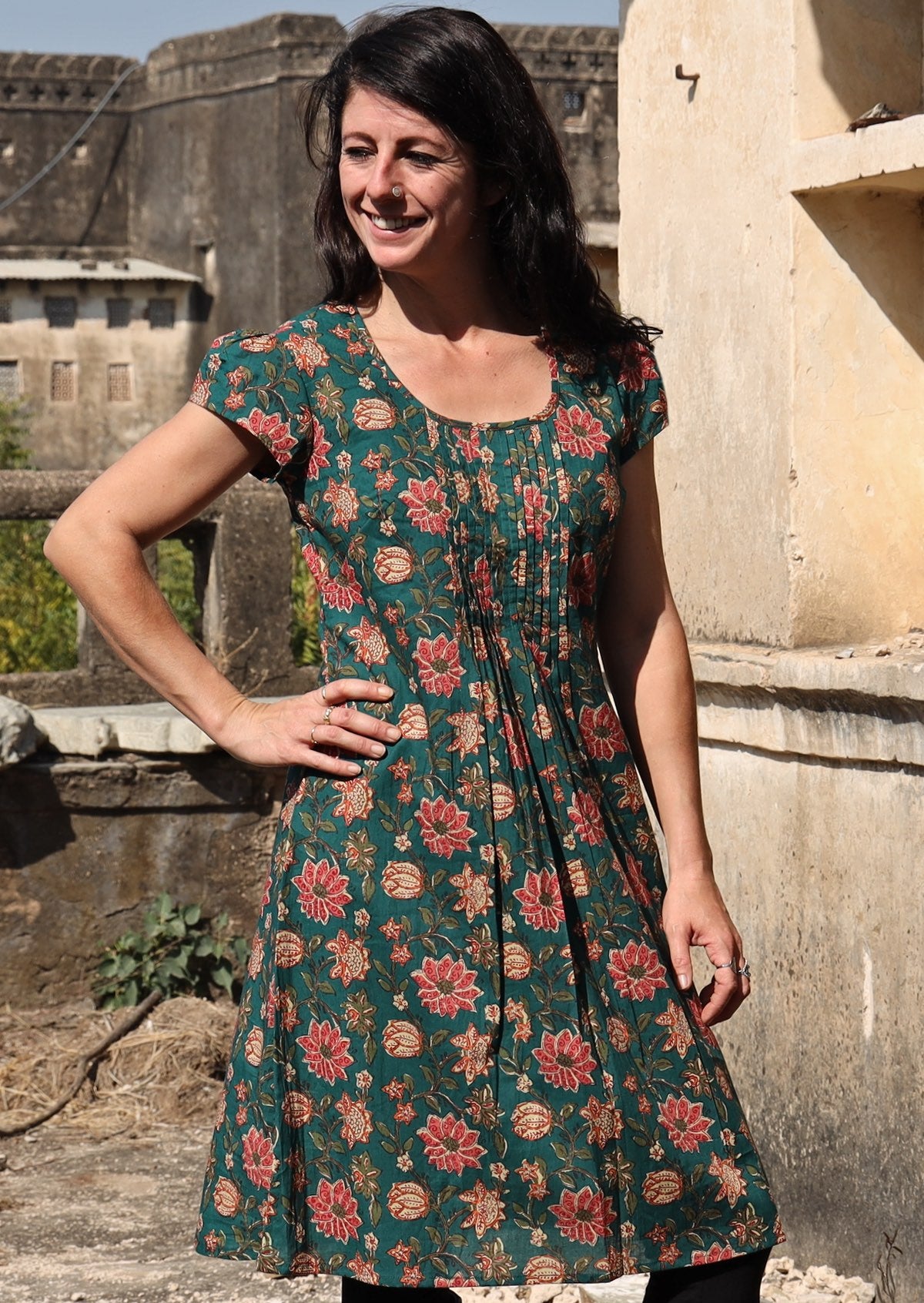 Women wears 100% cotton dress with pleated bodice, round neckline and short caped sleeves.