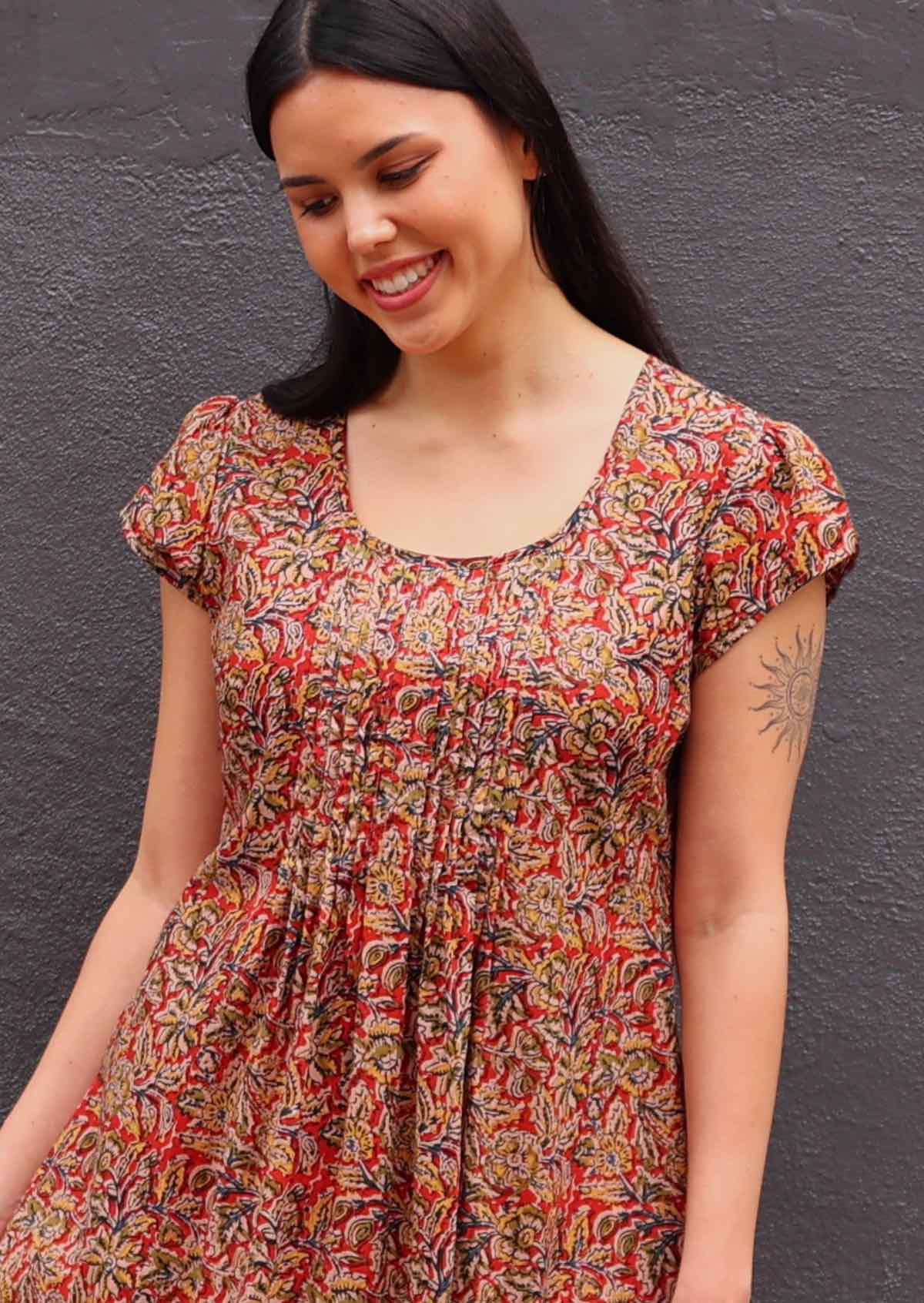 Woman with dark hair in Indian print cotton sundress, close up of neck detail- lots of pin tucks under scoop neckline