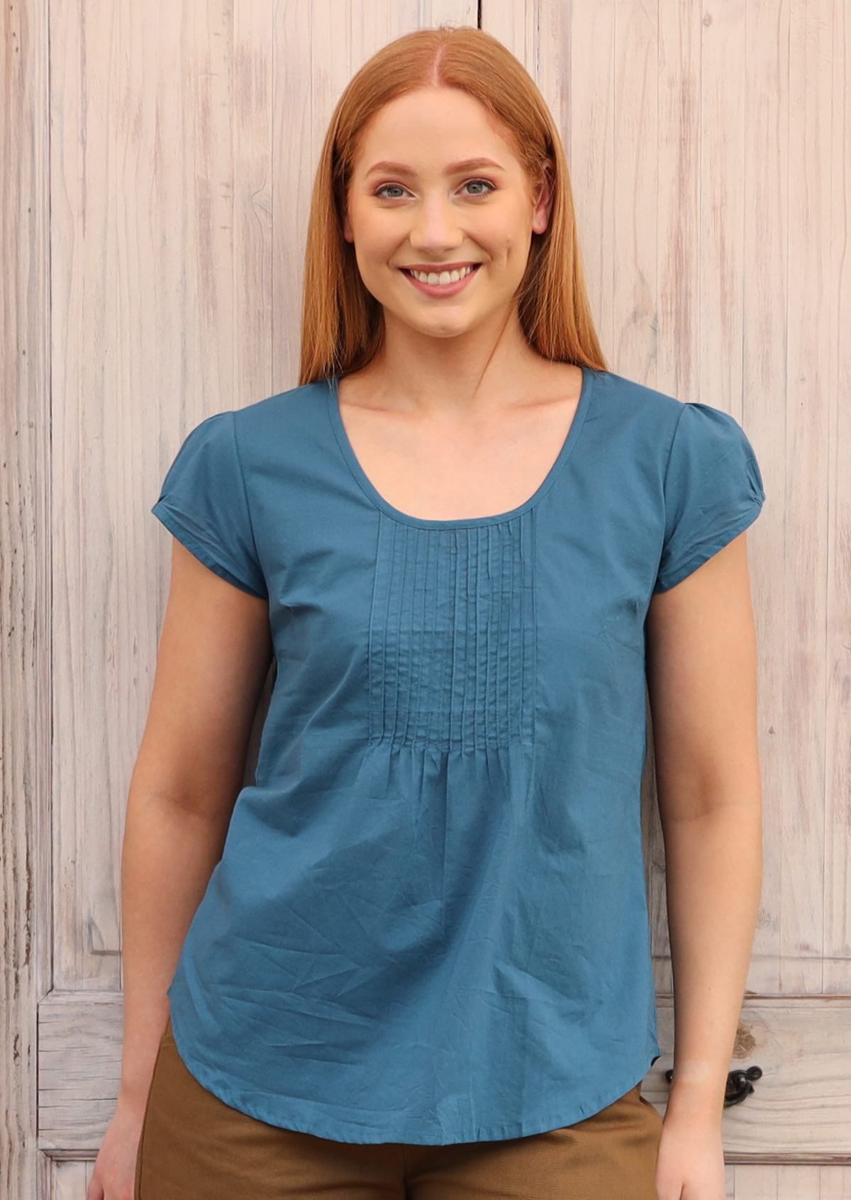 Model wears a top with cap sleeves and a U-shaped neckline.