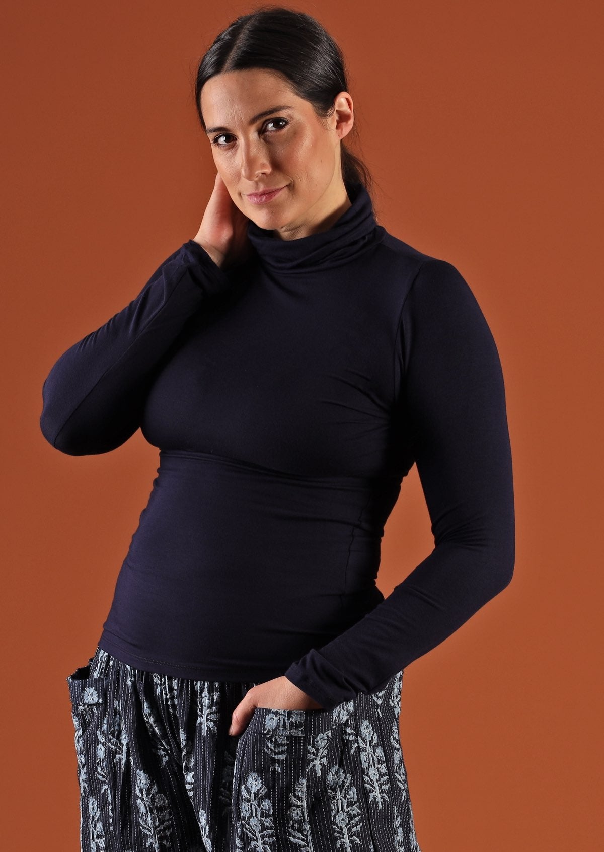 Woman wearing a turtle neck navy blue fitted long sleeve soft stretch rayon top with floral pants.