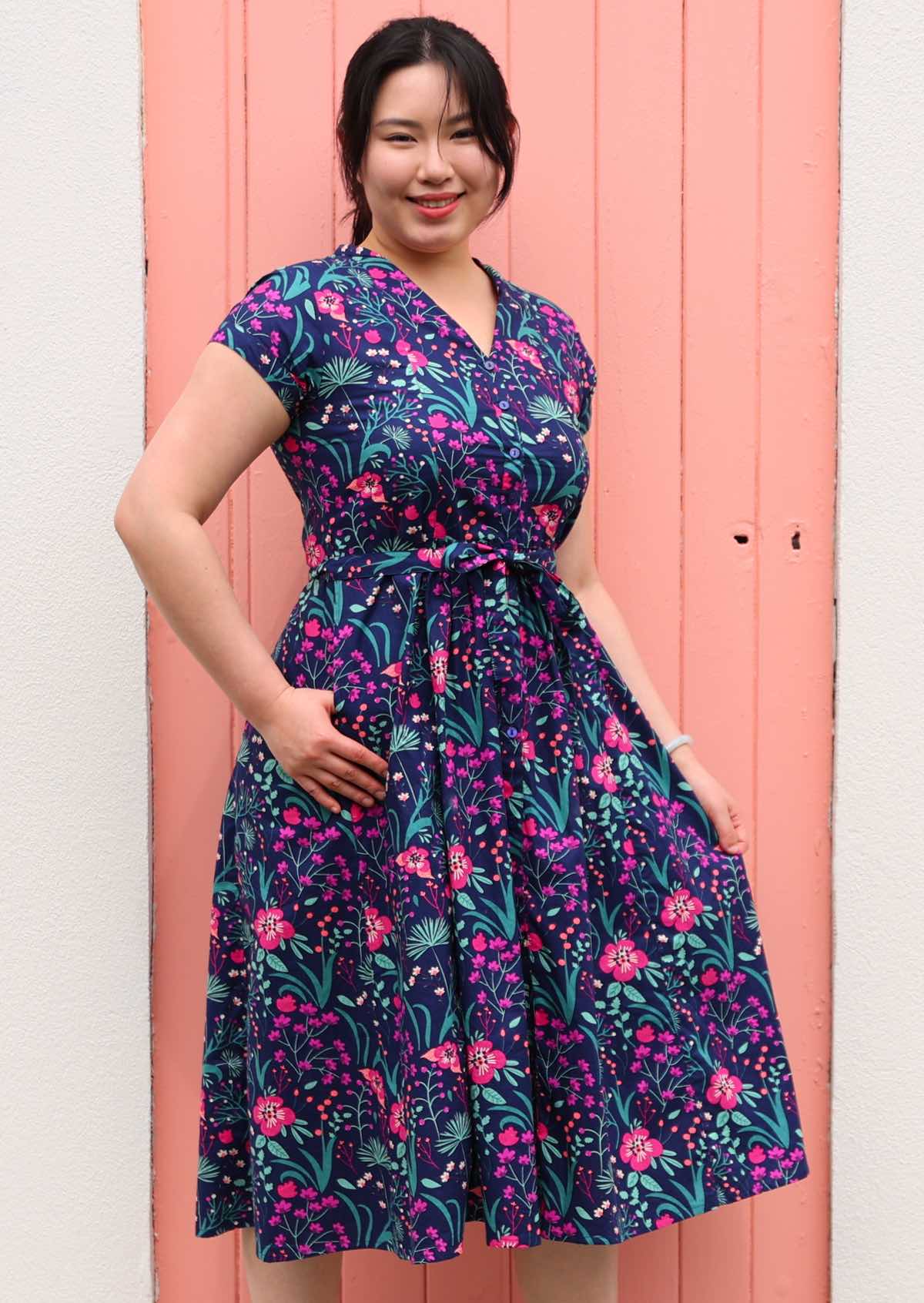 Woman standing in Navy cotton floral maxi dress with v-neck and hand in pockets