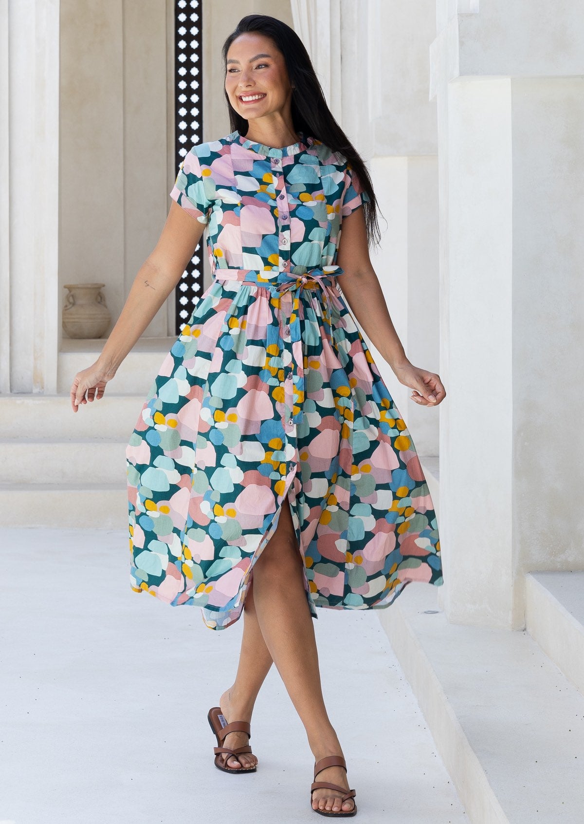 Woman skips in cotton 50's style button through midi length dress in pastel colours