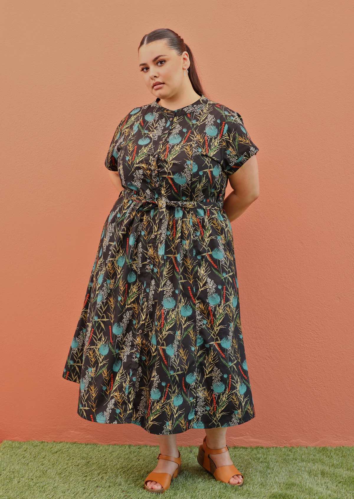 Plus size model wearing Vivien dress in black and teal with pockets and buttons up front