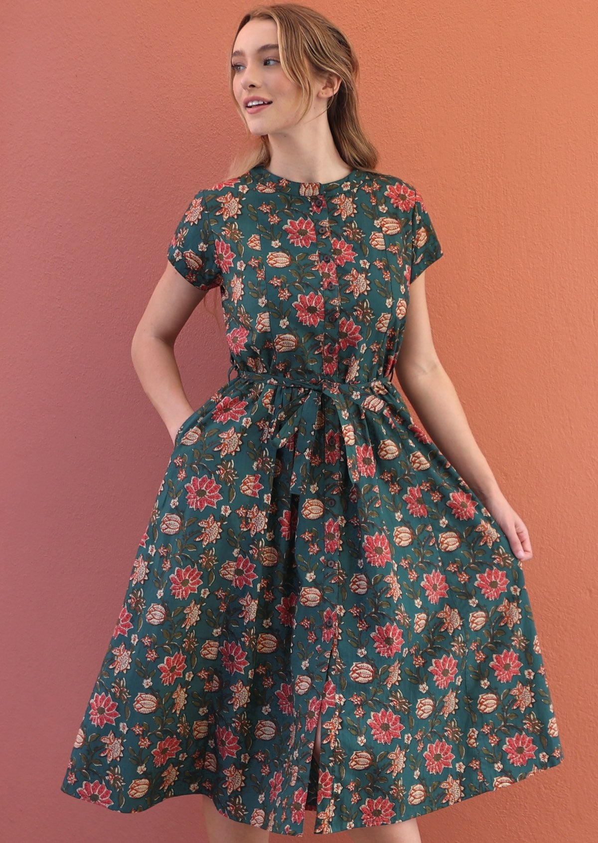 Model wears floral printed cotton dress in dark green colour.