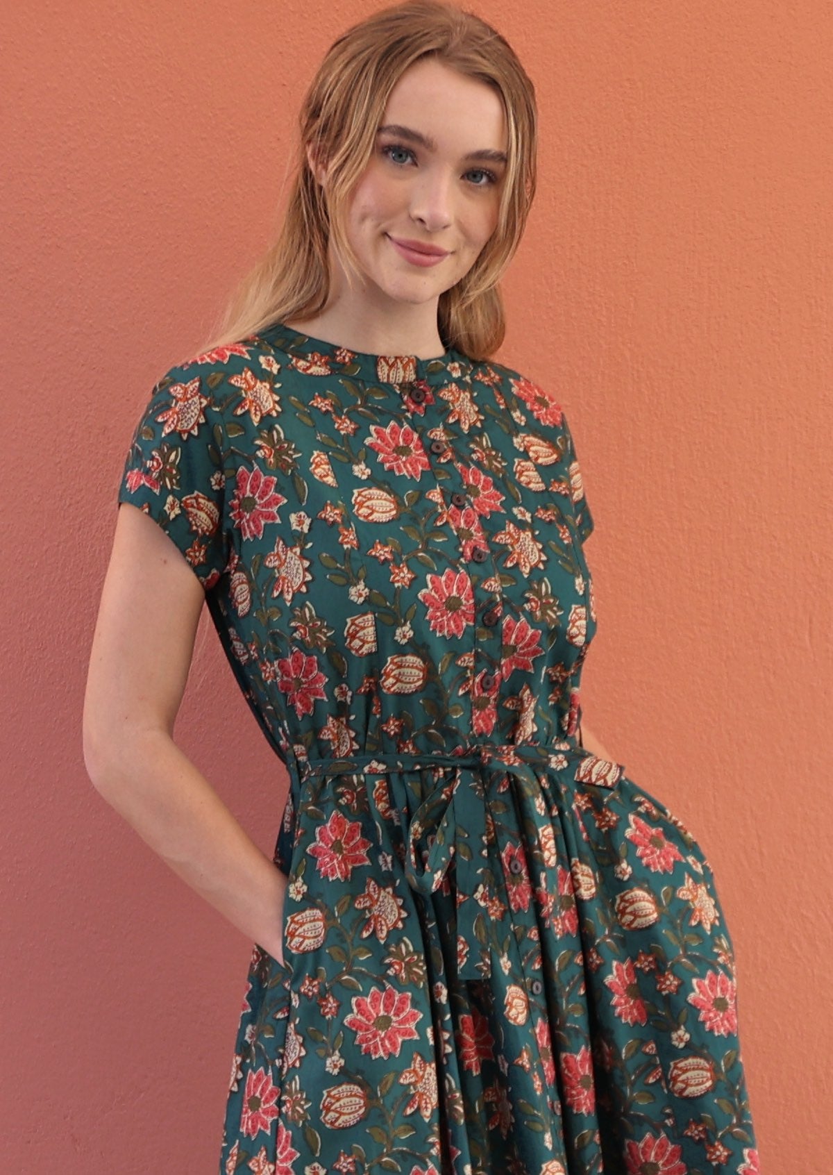 close look of button through vivien dress in dark green based floral print with pockets and belt.