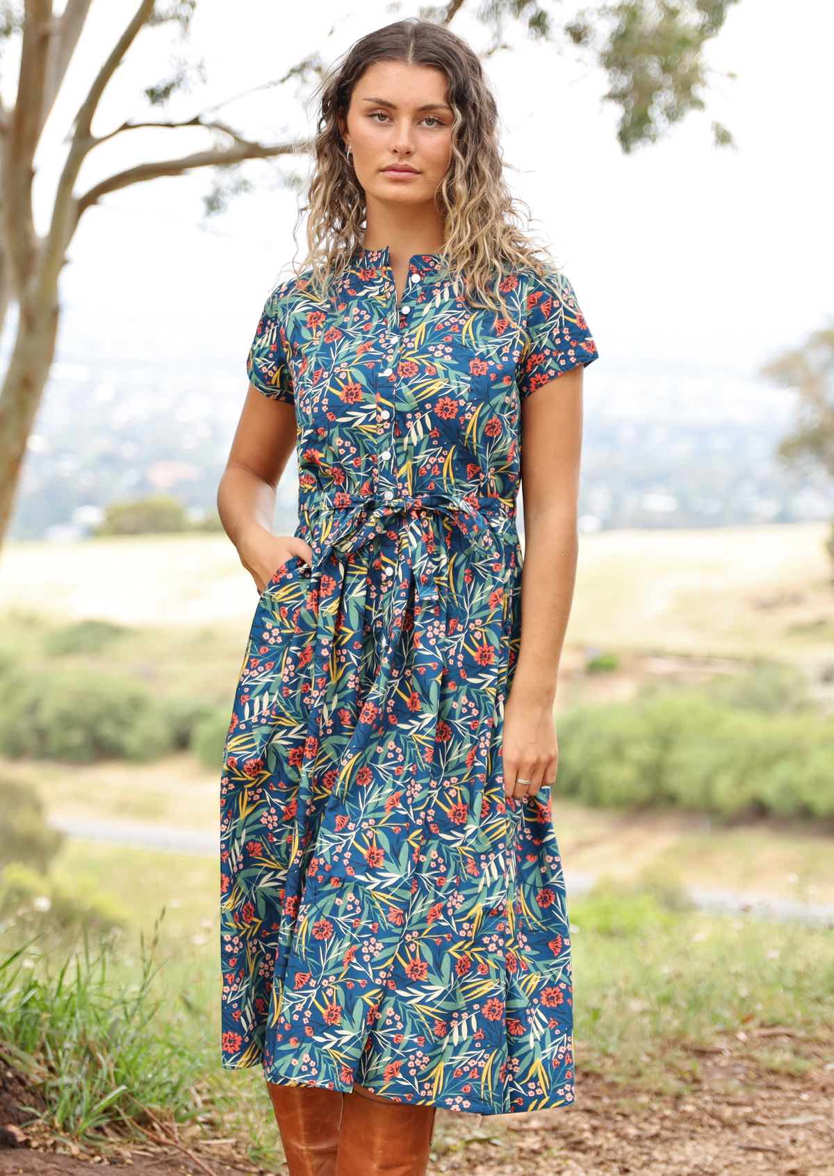 woman wearing floral button up retro style dress, hills in background
