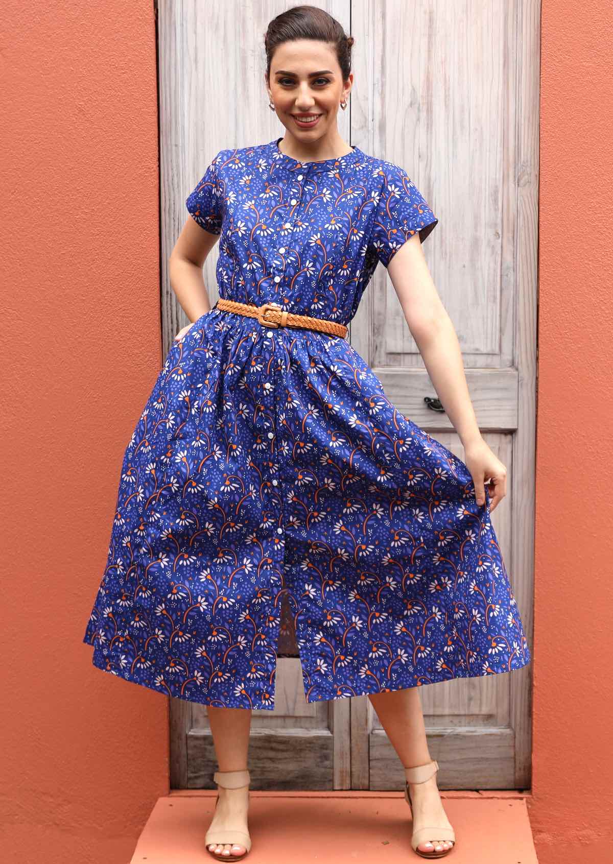 Model wears blue cotton dress with buttons down the front. 