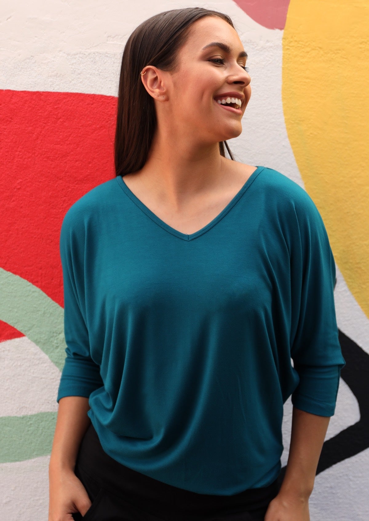 Woman wearing a 3/4 sleeve rayon batwing v-neck teal top.