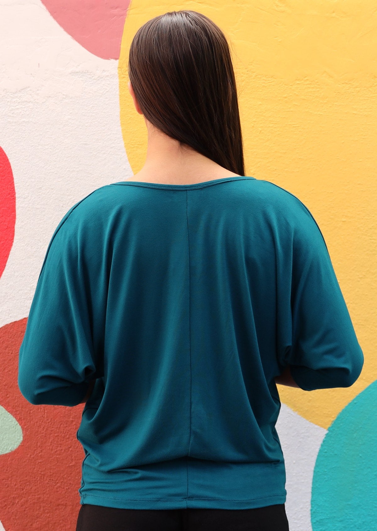 Back view of woman wearing 3/4 sleeve rayon batwing v-neck teal top.
