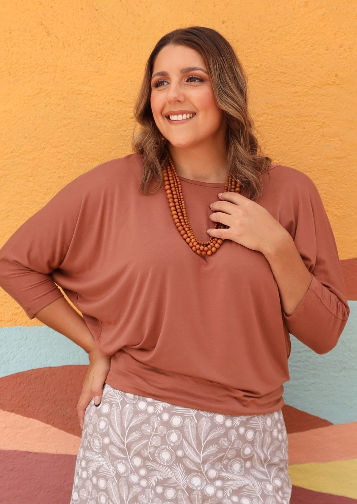 Woman wearing a 3/4 sleeve rayon batwing round neckline dusty pink top.