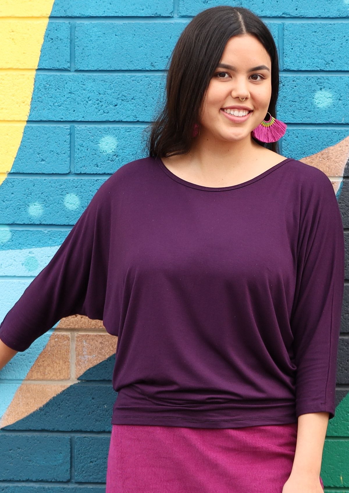 Woman wearing a 3/4 sleeve rayon batwing round neckline purple top.