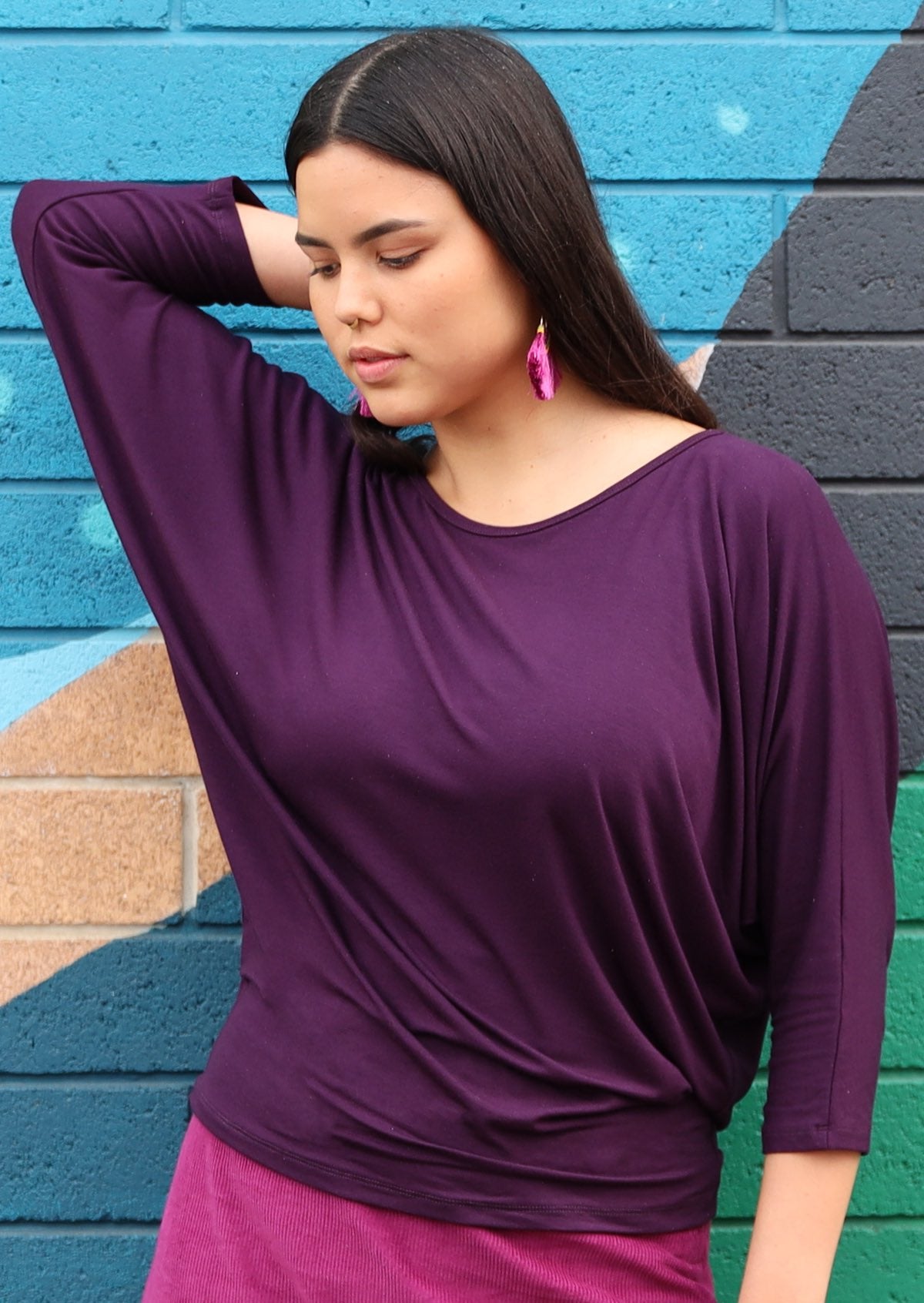 Woman with dark hair wearing a 3/4 sleeve rayon batwing round neckline purple top.