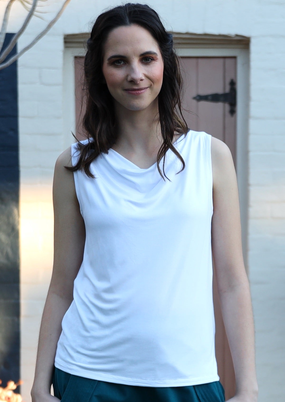 Woman with dark brown hair wearing white cowl neck rayon singlet top