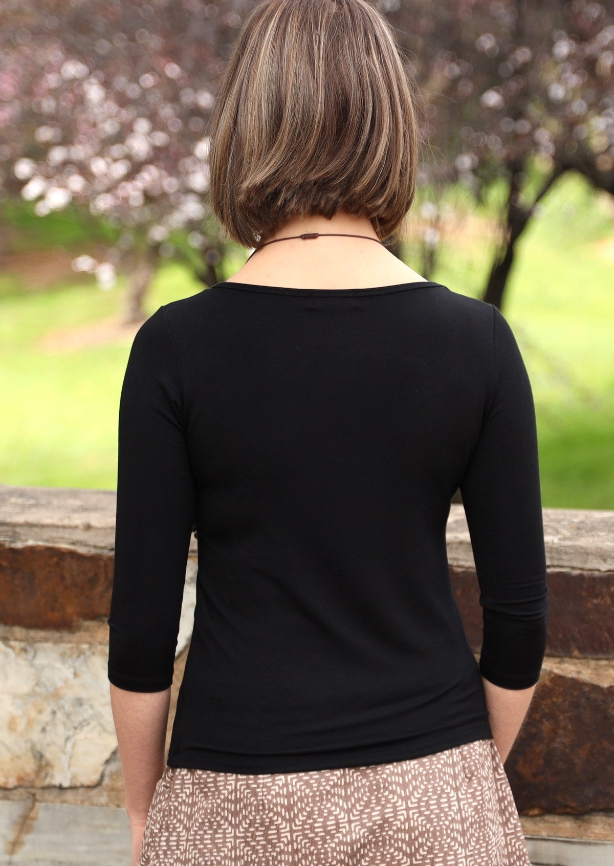 Back view of woman wearing a rayon boat neck black 3/4 sleeve top