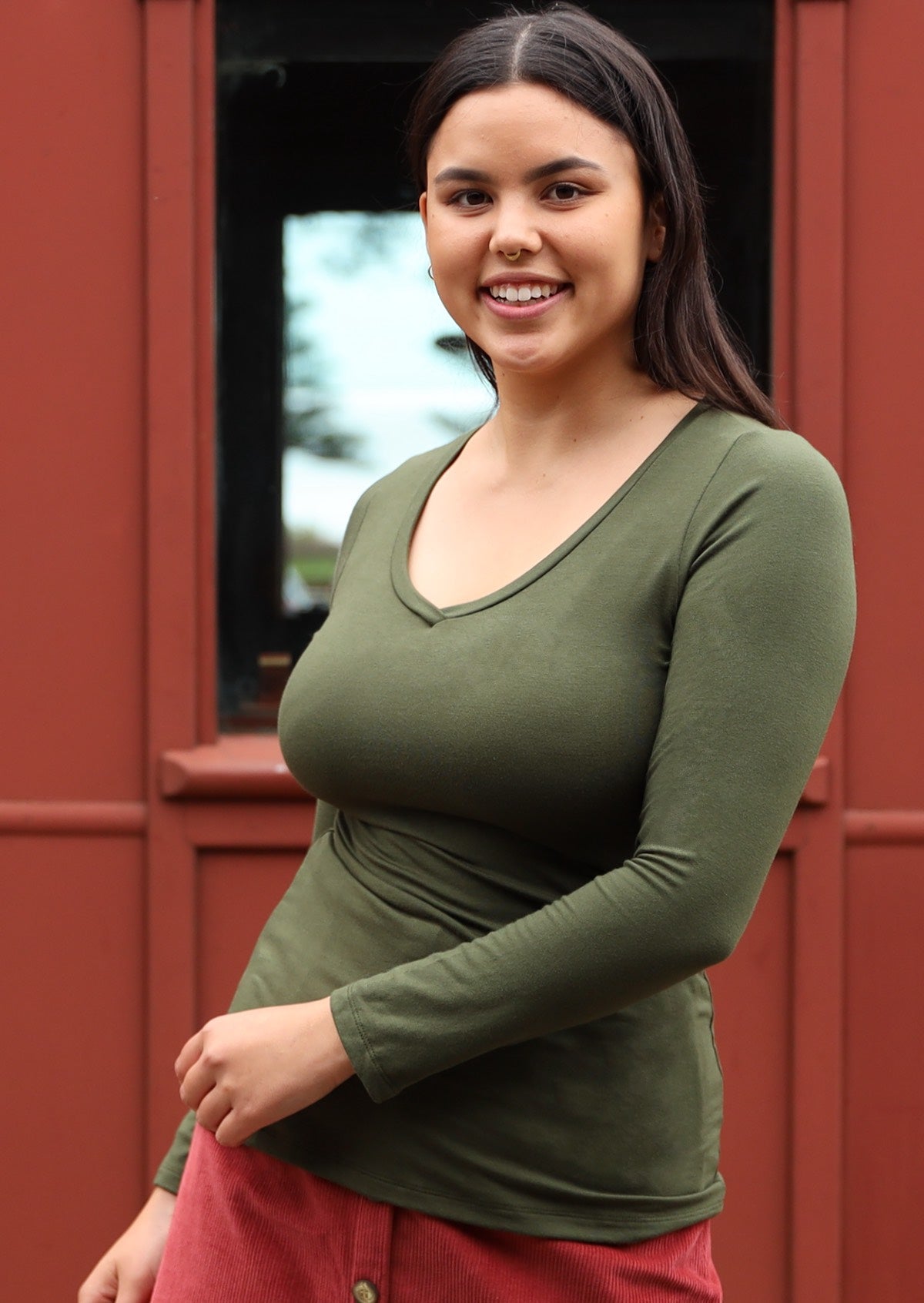 Woman wearing an olive green long sleeve stretch v-neck soft rayon top.