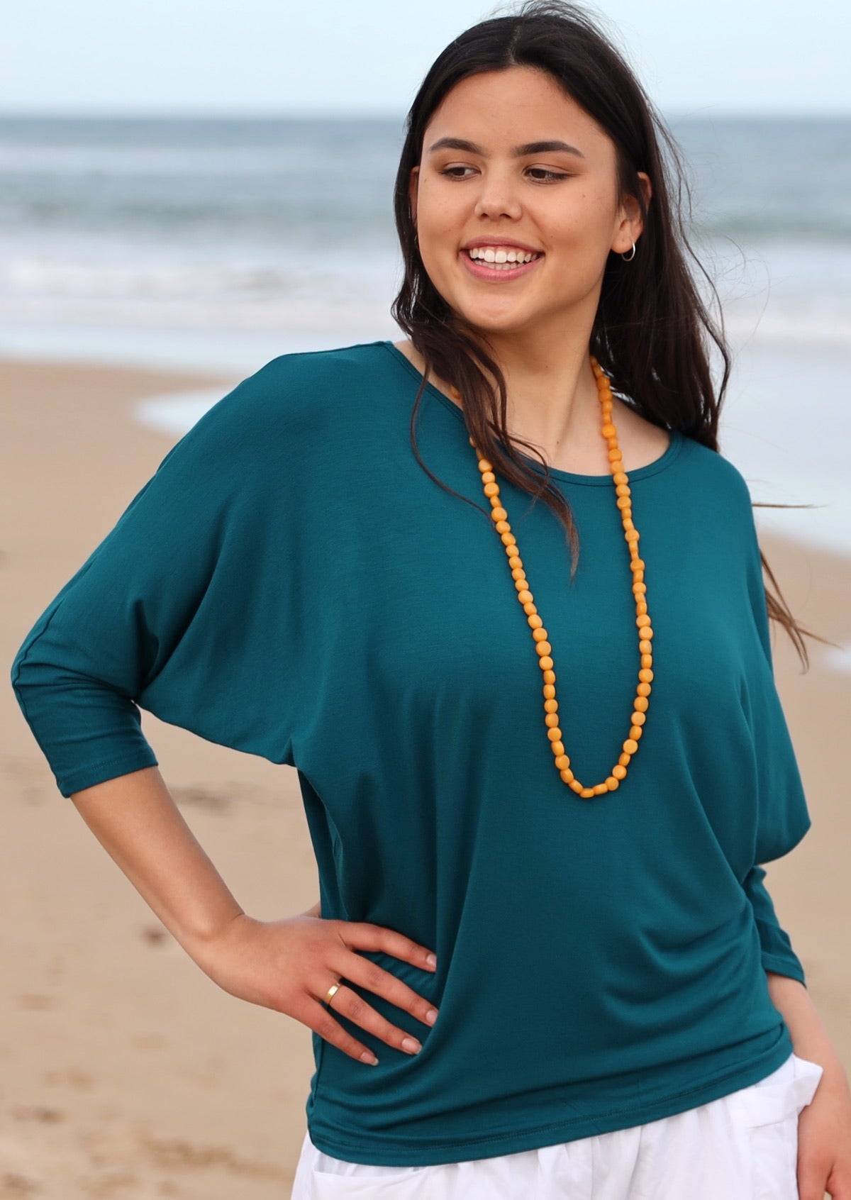 Woman wearing a 3/4 sleeve rayon batwing round neckline teal top.
