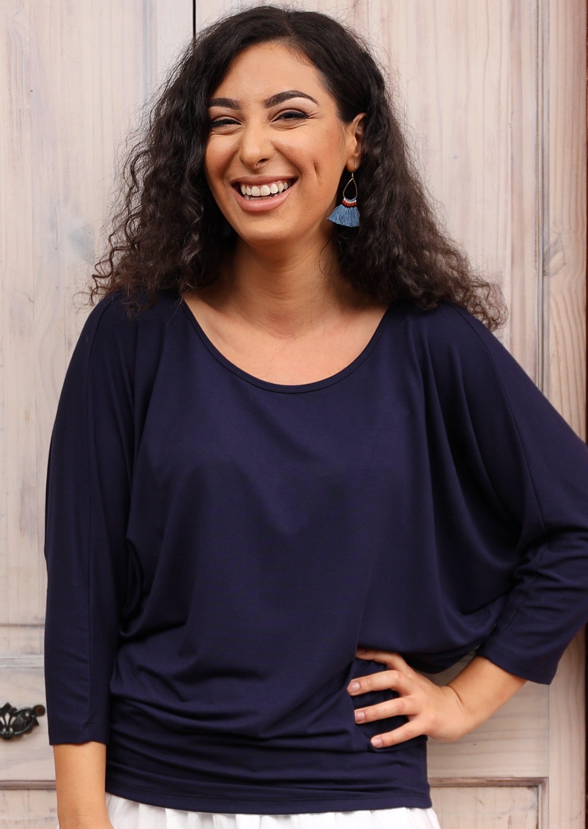 Woman wearing a 3/4 sleeve rayon batwing round neckline navy blue top.
